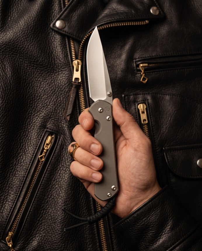 A Sebenza held against a leather jacket.