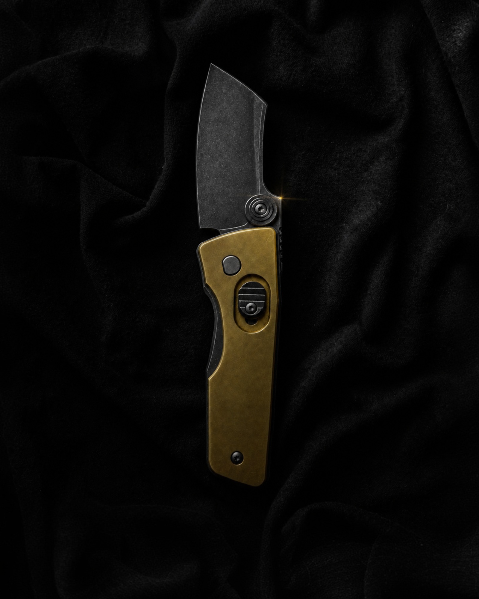 Serge Panchenko Guppy Midtech open on black velvet, the brass handle taking the only light.